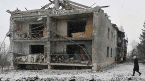 TOPSHOT - A local resident walks past a crater and a damaged residential building following a recent ...