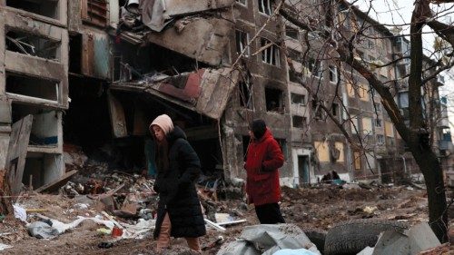 Local residents walk past an apartment building destroyed by a Russian missile attack in the town of ...
