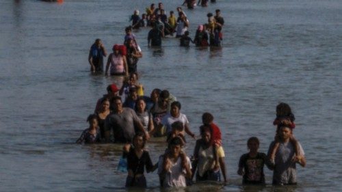 A caravan wades past a string of buoys, being constructed to deter migrants crossings through the ...