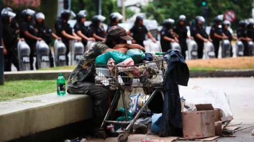 An homeless man sits in front of riot police as members of social organizations gather outside the ... An homeless man sits in front of riot police as members of social organizations gather outside the ...