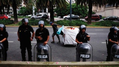 An urban recycler or 'cartonero' pushes his cart past riot police officers as members of social ... An urban recycler or 'cartonero' pushes his cart past riot police officers as members of social ...