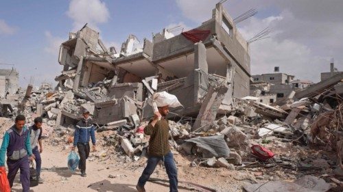 TOPSHOT - Displaced Palestinians carry their belongings through a street amid the rubble of houses ... TOPSHOT - Displaced Palestinians carry their belongings through a street amid the rubble of houses ...