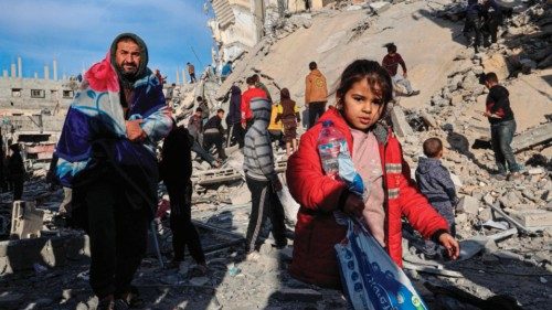 Palestinians walk away with some items salvaged from the rubble of a residential building hit in an ...