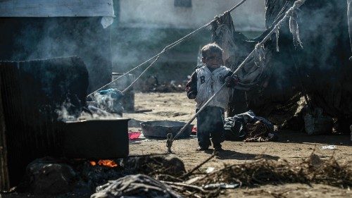 A displaced Syrian child stands near a makeshift stove using wood twigs for cooking, at the ...