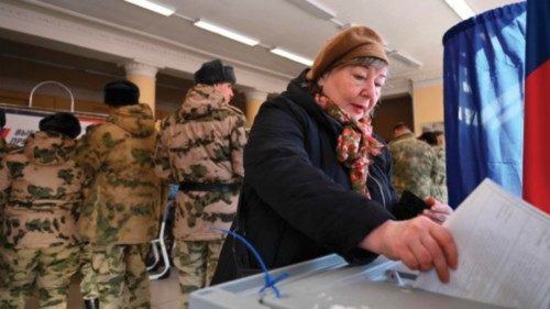 A woman casts her ballot as service members register to vote during Russia's presidential election ... A woman casts her ballot as service members register to vote during Russia's presidential election ...