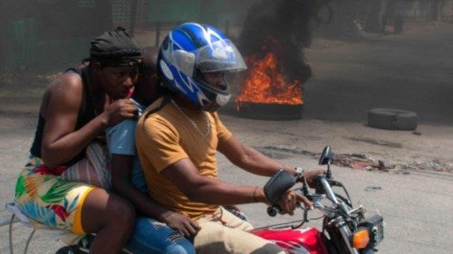 TOPSHOT - A woman with a child lowers her head as they leave the area on a motorcycle after gunshots ...