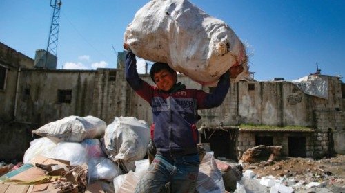 Saleh al-Hussein, a 13-year-old displaced Syrian boy, carries a bag of recyclable items at a rubbish ...