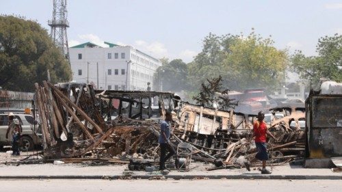 People walk past remains of vehicles near the presidential palace, after they were set on fire by ... People walk past remains of vehicles near the presidential palace, after they were set on fire by ...