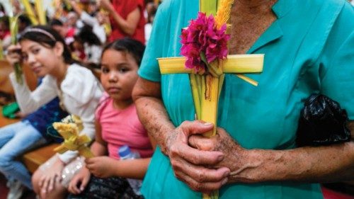 TOPSHOT - A woman holds palm crosses to be blessed during a Palm Sunday mass at the Metropolitan ...