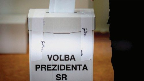 An person casts a ballot in a box reading 'election of the president of the republic' in a classroom ...