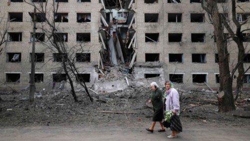 TOPSHOT - Elderly women walk past a hostel destroyed during a missile attack in the town of ...
