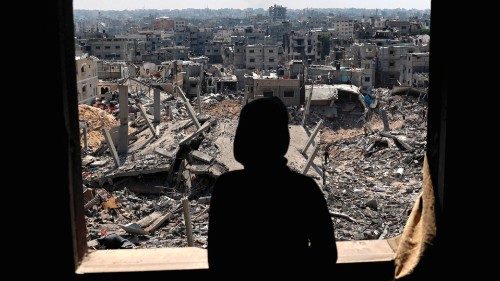TOPSHOT - A Palestinian youth looks out of a window at buildings destroyed during Israeli ...