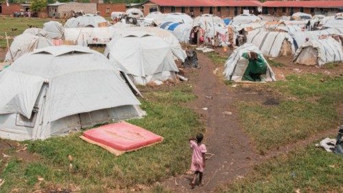 A girl walks next to tents and makeshift shelters in a temporary camp for displaced people following ... A girl walks next to tents and makeshift shelters in a temporary camp for displaced people following ...