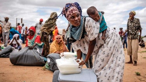 A woman who have been displaced from her home due to heavy floods carry her baby on the back while ... A woman who have been displaced from her home due to heavy floods carry her baby on the back while ...