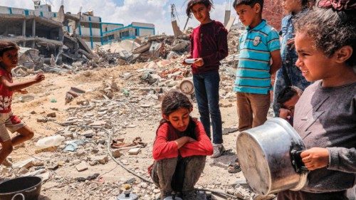 TOPSHOT - Children wait with pots to receive food rations from an outdoor kitchen in Khan Yunis in ...