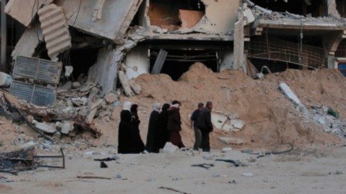 TOPSHOT - Displaced Palestinians walk in front of a building destroyed in Israeli bombardment in ... TOPSHOT - Displaced Palestinians walk in front of a building destroyed in Israeli bombardment in ...