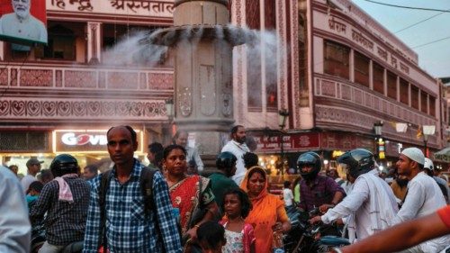 People walk past a water sprinkler installed on a pillar at a market place, amid heatwave in ... People walk past a water sprinkler installed on a pillar at a market place, amid heatwave in ...