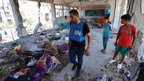 Palestinian boys watch as a member of a United Nations investigation team as he visits a school run ...