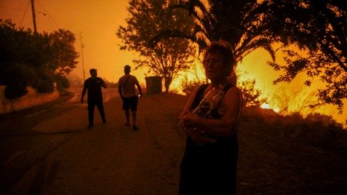 A local resident holds bottles of water next to a wildfire burning in the village of Latas, in ... A local resident holds bottles of water next to a wildfire burning in the village of Latas, in ...