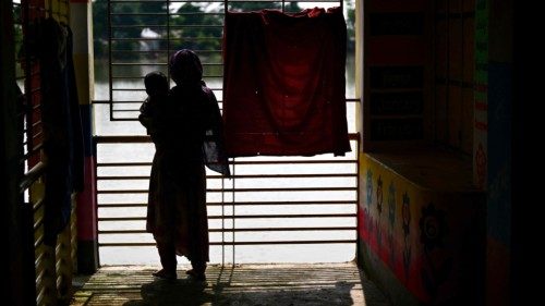 A woman holding her child looks out of a partially submerged temporary shelter in the flood-affected ... A woman holding her child looks out of a partially submerged temporary shelter in the flood-affected ...