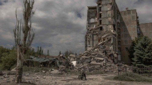 TOPSHOT - A local resident pushes a bicycle past a destroyed residential building following shelling ... TOPSHOT - A local resident pushes a bicycle past a destroyed residential building following shelling ...
