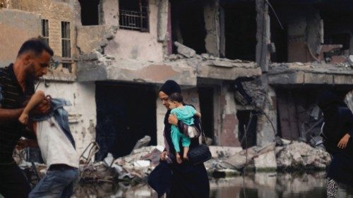 A woman holds a child as she walks next to buildings destroyed in an Israeli strike, amid the ... A woman holds a child as she walks next to buildings destroyed in an Israeli strike, amid the ...