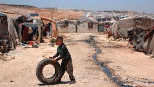 A Syrian boy plays with a tire near sewage canals that run between the tents at a camp for ...