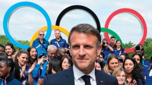 TOPSHOT - French President Emmanuel Macron looks on with the Olympic rings displayed behind him, ...