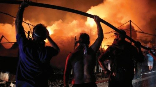 TOPSHOT - Volunteers hold a water hose in order to help firefighters extinguish a fire in a wood ...