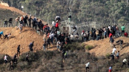 Migrants storm a barbed-wire fence as they attempt to cross the land border with Spain's African ... Migrants storm a barbed-wire fence as they attempt to cross the land border with Spain's African ...