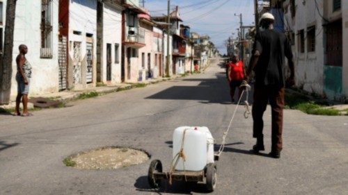 A man pulls a cart with a container of water from a church group that offers residents small ... A man pulls a cart with a container of water from a church group that offers residents small ...