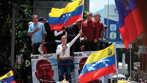 (FILES) Venezuelan opposition leader Maria Corina Machado (C) waves a national flag atop a truck ...
