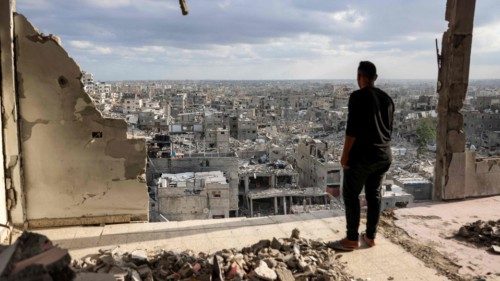 A man standing atop a heavily damaged building views other destroyed buildings in Khan Yunis in the ... A man standing atop a heavily damaged building views other destroyed buildings in Khan Yunis in the ...