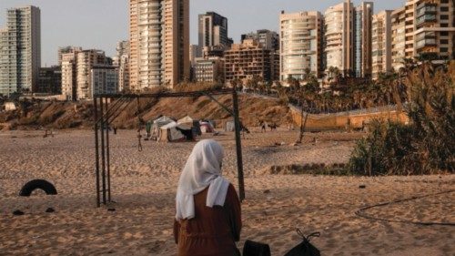 A displaced young woman sits by makeshift shelters on a Beirut beach, amid hostilities between ... A displaced young woman sits by makeshift shelters on a Beirut beach, amid hostilities between ...