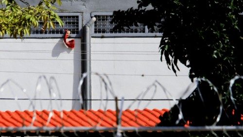A prisoner waves a red towel from inside the prison as relatives (not pictured) of people detained ... A prisoner waves a red towel from inside the prison as relatives (not pictured) of people detained ...