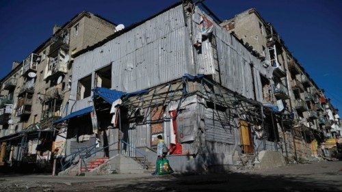 A woman walks past a store and residential buildings damaged as a result of a shelling in the city ... A woman walks past a store and residential buildings damaged as a result of a shelling in the city ...