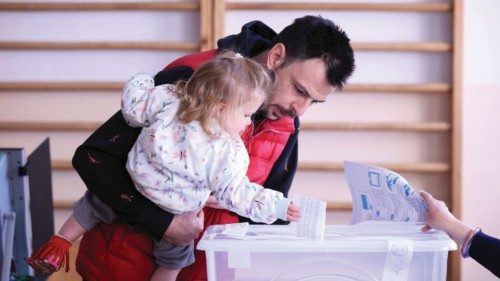 A man holds a child as he attends the snap parliamentary election, in Sofia, Bulgaria, October 27, ...