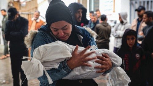 TOPSHOT - A woman mourns as she carries the shrouded body of a child killed following overnight ... TOPSHOT - A woman mourns as she carries the shrouded body of a child killed following overnight ...
