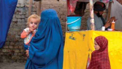 An Afghan burqa-clad woman carries a child as she walks along a road in Kandahar on October 29, ... An Afghan burqa-clad woman carries a child as she walks along a road in Kandahar on October 29, ...