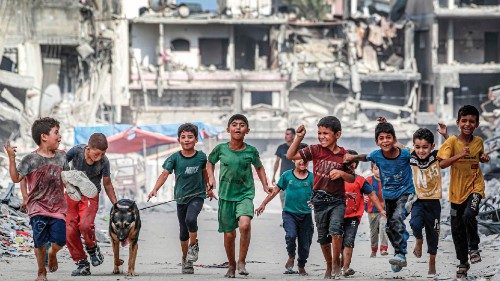 TOPSHOT - Children walk with a dog past destroyed buildings along a street in Khan Yunis in the ... TOPSHOT - Children walk with a dog past destroyed buildings along a street in Khan Yunis in the ...