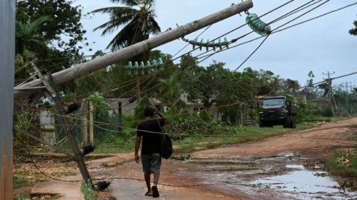 A man walks next to fallen power lines after the passage of hurricane Rafael in Alquizar, Artemisa ...