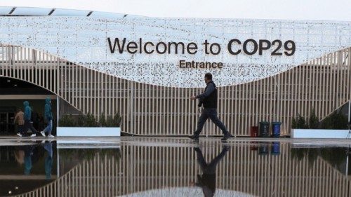 People walk in front of the venue of the United Nations climate change conference COP29, in Baku, ...