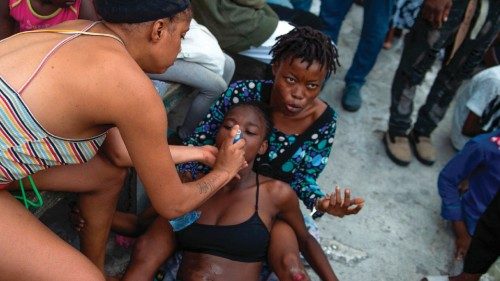 A woman receives aid after losing consciousness while fleeing her home due to armed gang violence in ...
