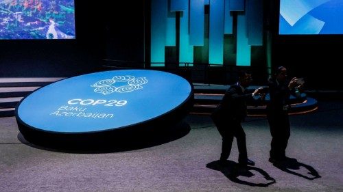 Delegates use their mobile phone as they stand next to an installation at the United Nations climate ...
