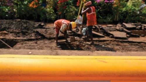 Labourers work at a site as a logo of Adani Electricity Mumbai Limited (AEML) is seen along the ... Labourers work at a site as a logo of Adani Electricity Mumbai Limited (AEML) is seen along the ...
