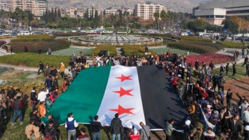 TOPSHOT - People hold a large Syrian opposition flag at Umayyad Square in Damascus on December 9, ... TOPSHOT - People hold a large Syrian opposition flag at Umayyad Square in Damascus on December 9, ...