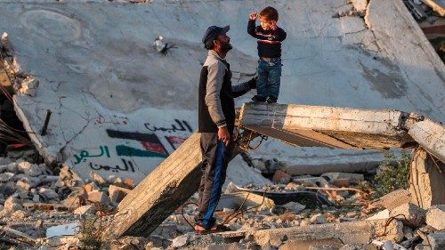 A man speaks with a boy standing on a broken concrete beam by the rubble of a collapsed building at ...
