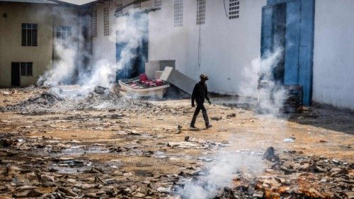 A man walks past the smoldering remains of boxes and materials left behind by looters after ... A man walks past the smoldering remains of boxes and materials left behind by looters after ...