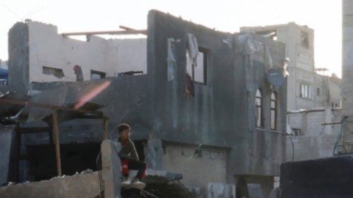 A child sits amid rubble as Palestinians inspect the site of an Israeli strike on a house, in Khan ...