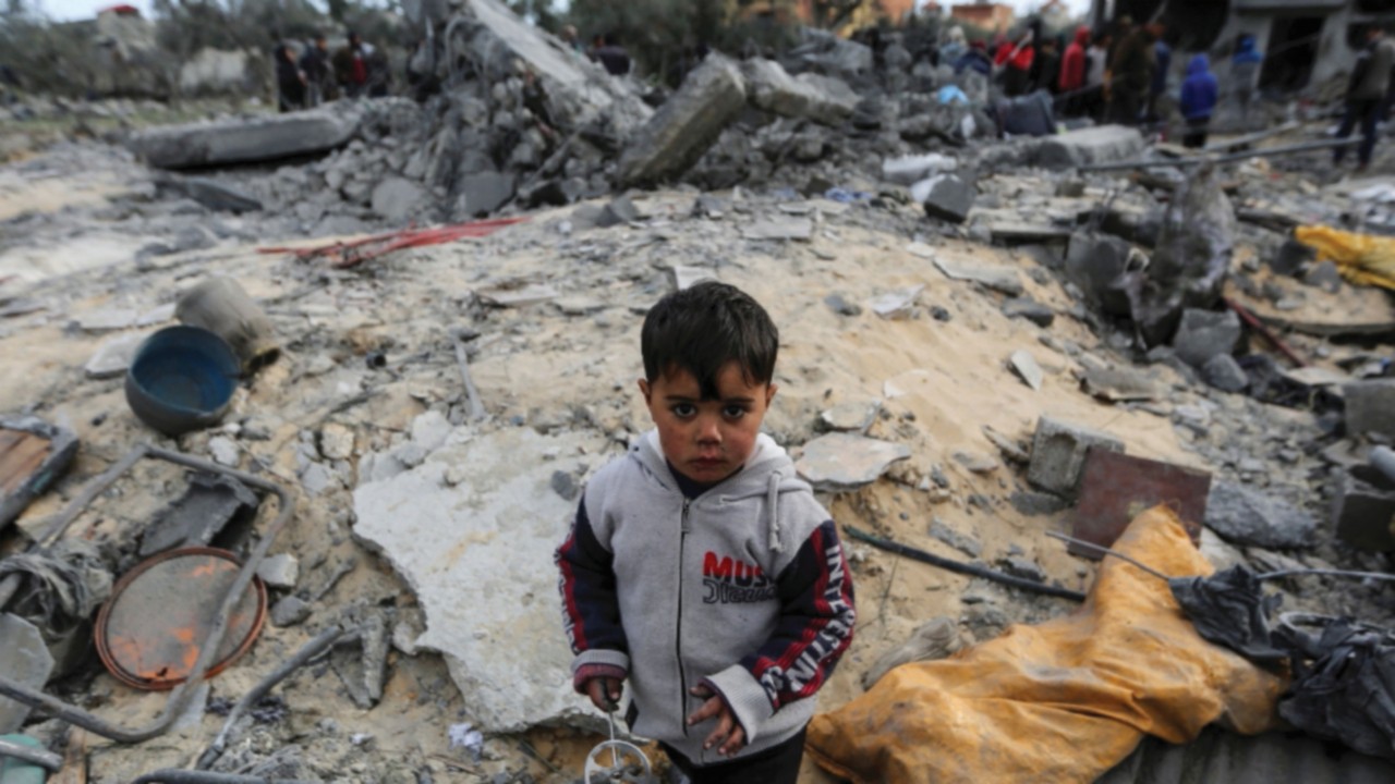 A child looks on as Palestinians inspect the site of an Israeli strike on a house, in Khan Younis in ...